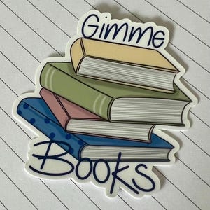May include: A sticker featuring a stack of books in various colors, including yellow, green, pink, and blue. The words "Gimme Books" are written in a whimsical font above and below the books. The sticker is on a lined paper background.