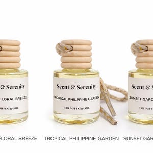 May include: Three glass car air fresheners with wooden tops and hanging cords. Each bottle has a label that reads "Scent & Serenity" and a scent name: "Filipino Floral Breeze", "Tropical Philippine Garden", and "Sunset Garden Whisper".