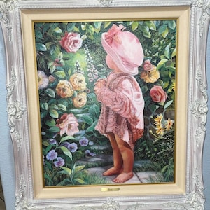 Könnte beinhalten: Gerahmtes Gemälde eines Kindes in rosa Kleid und Hut in einem Garten mit Rosen und anderen Blumen. Das Gemälde hat einen weißen, verzierten Rahmen. Das Kind ist von hinten zu sehen, was eine weiche, verträumte Atmosphäre schafft.