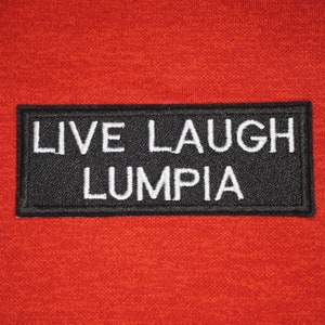 May include: Black and white embroidered patch with the text "LIVE LAUGH LUMPIA" on a red background.