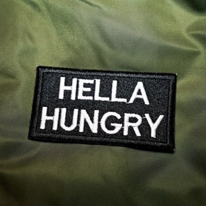 May include: A black patch with white text that reads "HELLA HUNGRY" on a green background.