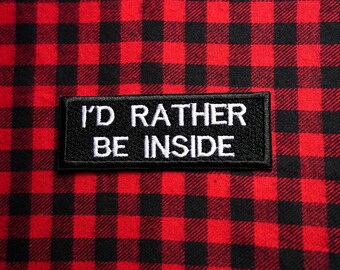 May include: Black and white embroidered patch with the text "I'd rather be inside" on a red and black plaid background.