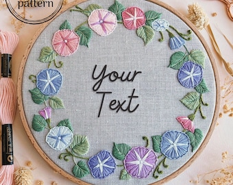 May include: A gray embroidery hoop with a floral design of blue, pink, and purple flowers. The text "your text" is embroidered in the center of the hoop.