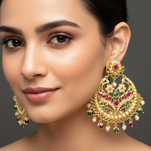 Peut inclure: Boucles d'oreilles dorées ornées, avec un motif floral et en forme de goutte. Elles présentent des pierres précieuses rouges, vertes et blanches, avec des perles pendantes. Les boucles d'oreilles sont grandes et accrocheuses.
