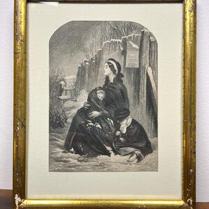 May include: An antique framed print depicting a winter scene with figures in a snowy landscape. The print is in a gold-colored frame with visible wear. The artwork shows a woman and child, with another figure kneeling in the snow.