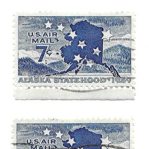 May include: Three vintage U.S. Air Mail stamps. Each stamp features a blue outline of Alaska with white stars, the text "U.S. AIR MAIL", and the number "7". The text "ALASKA STATEHOOD 1959" is also visible.