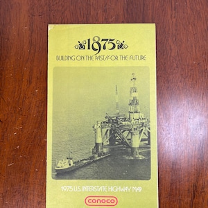 May include: A vintage 1975 U.S. Interstate Highway Map from Conoco, featuring an illustration of an offshore oil rig. The cover is a light green color with the text "1875" and "BUILDING ON THE PAST/FOR THE FUTURE".