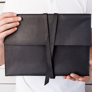 May include: A black leather envelope with a black ribbon closure.