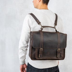 Puede incluir: Un malet&iacute;n de cuero marr&oacute;n con correas ajustables, usado como mochila. La bolsa tiene un asa superior y dos hebillas en la parte delantera.