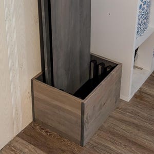 May include: A set of three gray wooden table leaves stored in a matching wooden box. The box has a dark interior and is designed to hold the leaves upright. The wood has a visible grain.