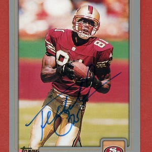 May include: A 2001 Topps football card featuring Terrell Owens, a wide receiver for the San Francisco 49ers. The card is signed in blue ink by Owens. The card is in a silver frame with a red background.
