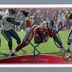 May include: A Topps football trading card depicting Frank Gore of the 49ers in a red and gold uniform. The card shows Gore diving with the football, with the 49ers logo and his name at the bottom.