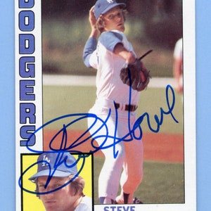May include: A baseball card featuring Steve Howe, a pitcher for the Los Angeles Dodgers. The card is from the Topps series and features a photo of Howe pitching, along with his signature and a smaller photo of him in a close-up.