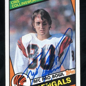 May include: A vintage Topps football trading card featuring Cris Collinsworth, a wide receiver for the Cincinnati Bengals. The card is orange, green, and white with a photo of Collinsworth in his uniform. The card has the text "Cris Collinsworth", "AFC Pro Bowl", "Bengals", and "WR" on it.