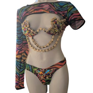 May include: A three-piece swimsuit set with a zebra print. The set includes a top with short sleeves, a bra with a jeweled embellishment, and a bottom with a jeweled embellishment.