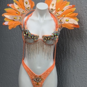 May include: A peach-colored, beaded and sequined costume with a matching feather headdress. The costume features a halter top with a fringe bottom and a matching bottom with a beaded design.