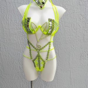 May include: A neon green, beaded, and sequined costume with a matching necklace. The costume features a halter top, a body suit, and a beaded chain.