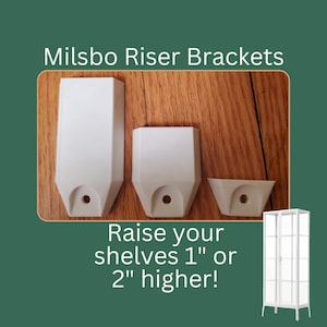 May include: Three white plastic shelf riser brackets, two are 1 inch tall and one is 2 inches tall. The brackets are designed to raise shelves in a cabinet or bookcase. The text "Raise your shelves 1" or 2" higher!" is below the brackets. A white cabinet with glass doors is in the lower right corner of the image.