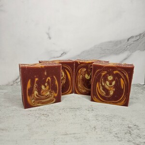 May include: Four bars of handmade soap with a swirl pattern of red and orange.