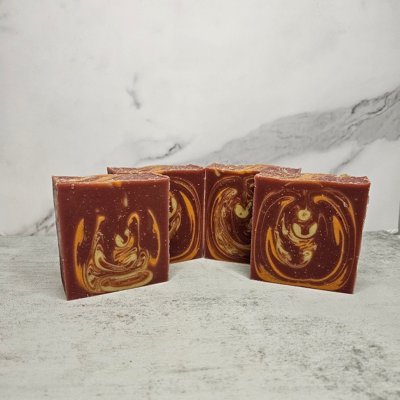 May include: Four bars of handmade soap with a swirl pattern of red and orange.