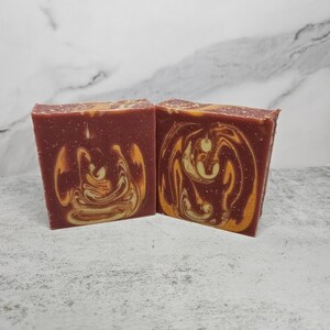 May include: Two bars of handmade soap with a swirl pattern in shades of red, orange, and yellow.
