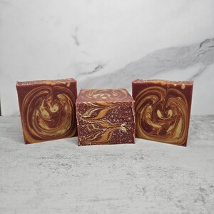 May include: Three bars of handmade soap with a swirl pattern in shades of brown and orange.