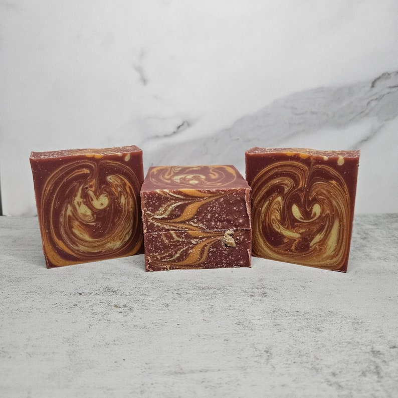 May include: Three bars of handmade soap with a swirl pattern in shades of brown and orange.