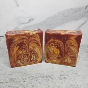 May include: Two bars of handmade soap with a swirl pattern of red and yellow.