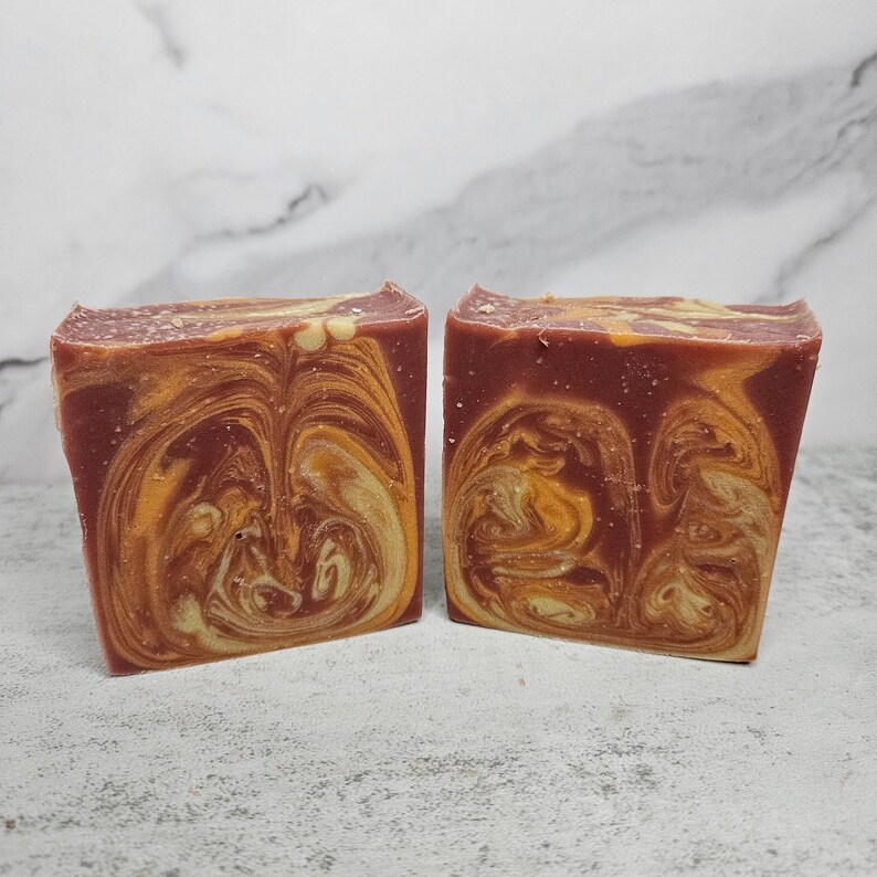 May include: Two bars of handmade soap with a swirl pattern of red and yellow.