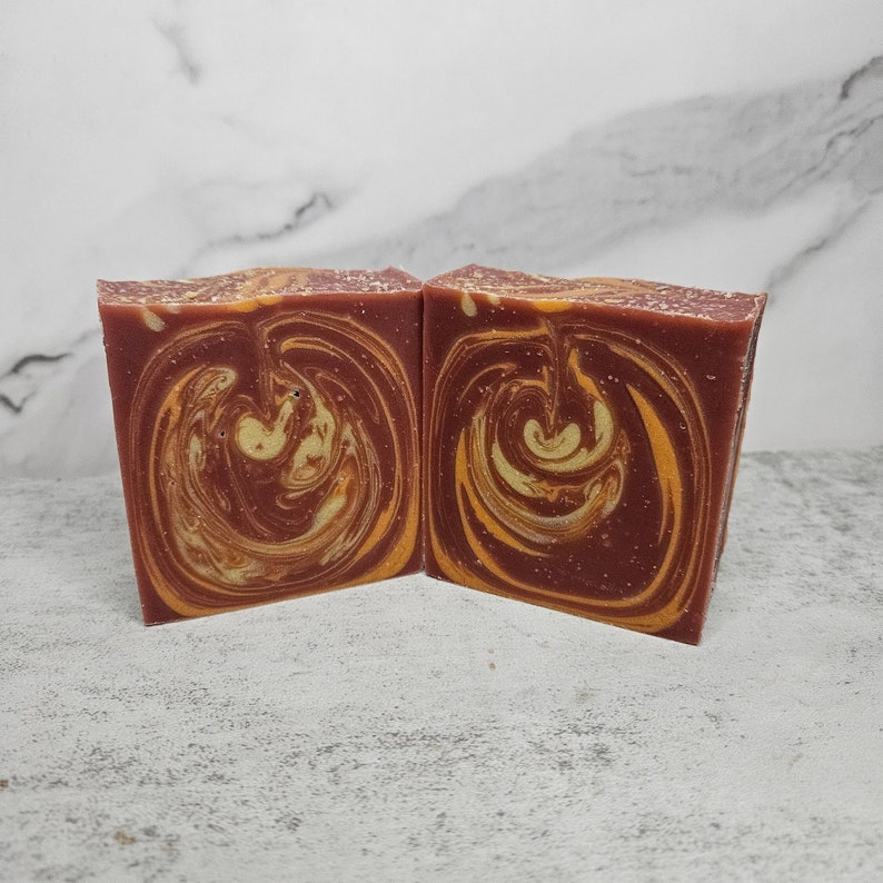 May include: Two bars of handmade soap with a swirl pattern in shades of brown and yellow.