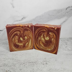 May include: Two bars of handmade soap with a swirl pattern in shades of red and yellow.
