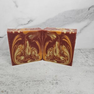 May include: Two bars of handmade soap with a swirl pattern in shades of red, orange, and yellow.