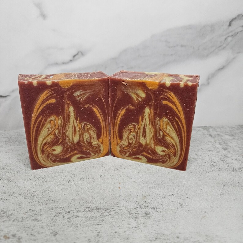 May include: Two bars of handmade soap with a swirl pattern in shades of red, orange, and yellow.