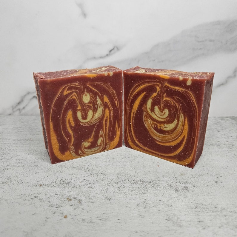 May include: Two bars of handmade soap with a swirl pattern in shades of red and yellow.