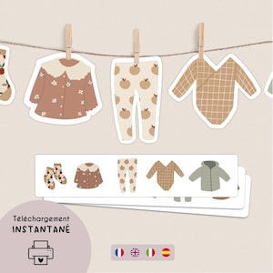 Op de afbeelding: Een verzameling stickeruitsparingen van kinderkleding, waaronder een bruine top met bloemen, een broek met appelprint en een geruite onesie, hangend aan een touwtje met wasknijpers. De afbeelding bevat ook een stapel kledingstickers en de tekst "Téléchargement INSTANTANÉ".