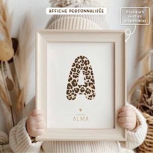 Peut inclure: Une affiche personnalisée avec une grande lettre A en motif léopard. La lettre est dans un schéma de couleurs brun clair et beige. L'affiche comprend également le nom "ALMA" en couleur or.