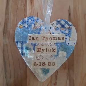 May include: A blue and white patchwork heart-shaped ornament with the text "Ian Thomas Hyink 8.18.20" on it.
