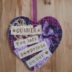 May include: Purple patchwork heart with the words "Gunner you left paw prints on our" and a small heart.