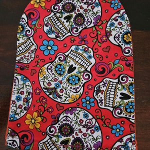 Könnte beinhalten: Roter Stoff mit einem sich wiederholenden Muster aus weißen Zucker Schädeln mit bunten floralen Details. Die Schädel haben schwarze Augen und sind von rosa, blauen, gelben und violetten Blumen umgeben.