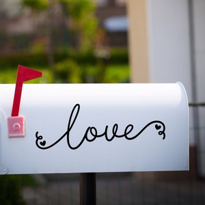 May include: White mailbox with a red flag and the word "love" written in black cursive with two small hearts.