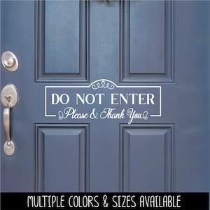 May include: A white vinyl decal applied to a dark blue door. The decal features a rectangular border with decorative flourishes and the text "DO NOT ENTER" in a bold, sans-serif font, followed by "Please & Thank You" in a cursive script font.