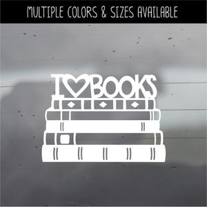 May include: A white vinyl decal featuring a stack of three books with the text I HEART BOOKS above them, where the heart is a solid shape. The top of the image includes the text MULTIPLE COLORS & SIZES AVAILABLE in a white sans-serif font.