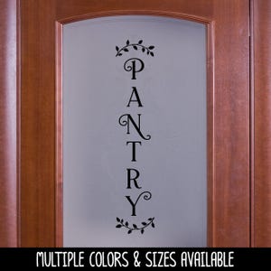 May include: A vertical black vinyl decal applied to a frosted glass door panel. The decal features the word PANTRY in a decorative serif font, oriented vertically, with small leafy vine flourishes positioned above and below the text.