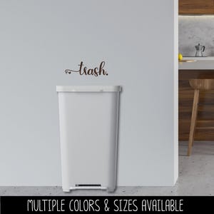 May include: A white rectangular trash can with a foot pedal, set against a white wall. Above the can, the word "trash" is written in a cursive font. The text "MULTIPLE COLORS & SIZES AVAILABLE" is at the bottom.