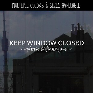 May include: White vinyl decal with the text "KEEP WINDOW CLOSED - please & thank you" on a glass window. The window reflects a building with multiple chimneys.