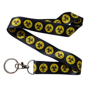 May include: Black lanyard with repeating yellow biohazard symbols. The lanyard has a metal clasp and key ring. The lanyard is made of a smooth, satin-like material.
