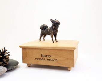 May include: A wooden pet urn with a small bronze chihuahua figurine on top. The urn is engraved with the name "Harry" and the dates "03/10/93 - 04/05/21".