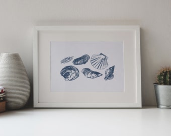 May include: A white framed print with a blue illustration of various seashells. The print features a scallop shell, oyster shells, and a conch shell.