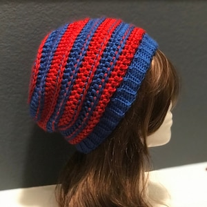 May include: A blue and red striped crocheted beanie hat. The hat is slouchy and has a ribbed texture.