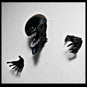 Puede incluir: Una cabeza de alienígena negra con dientes afilados y un par de manos de alienígena negras con garras. La cabeza y las manos del alienígena están montadas en una pared blanca texturizada.